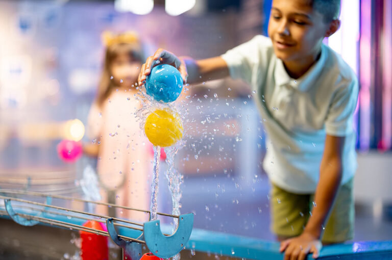 Junge spielt mit einem Wasserstrahl an einem interaktiven Modell im Erlebnismuseum